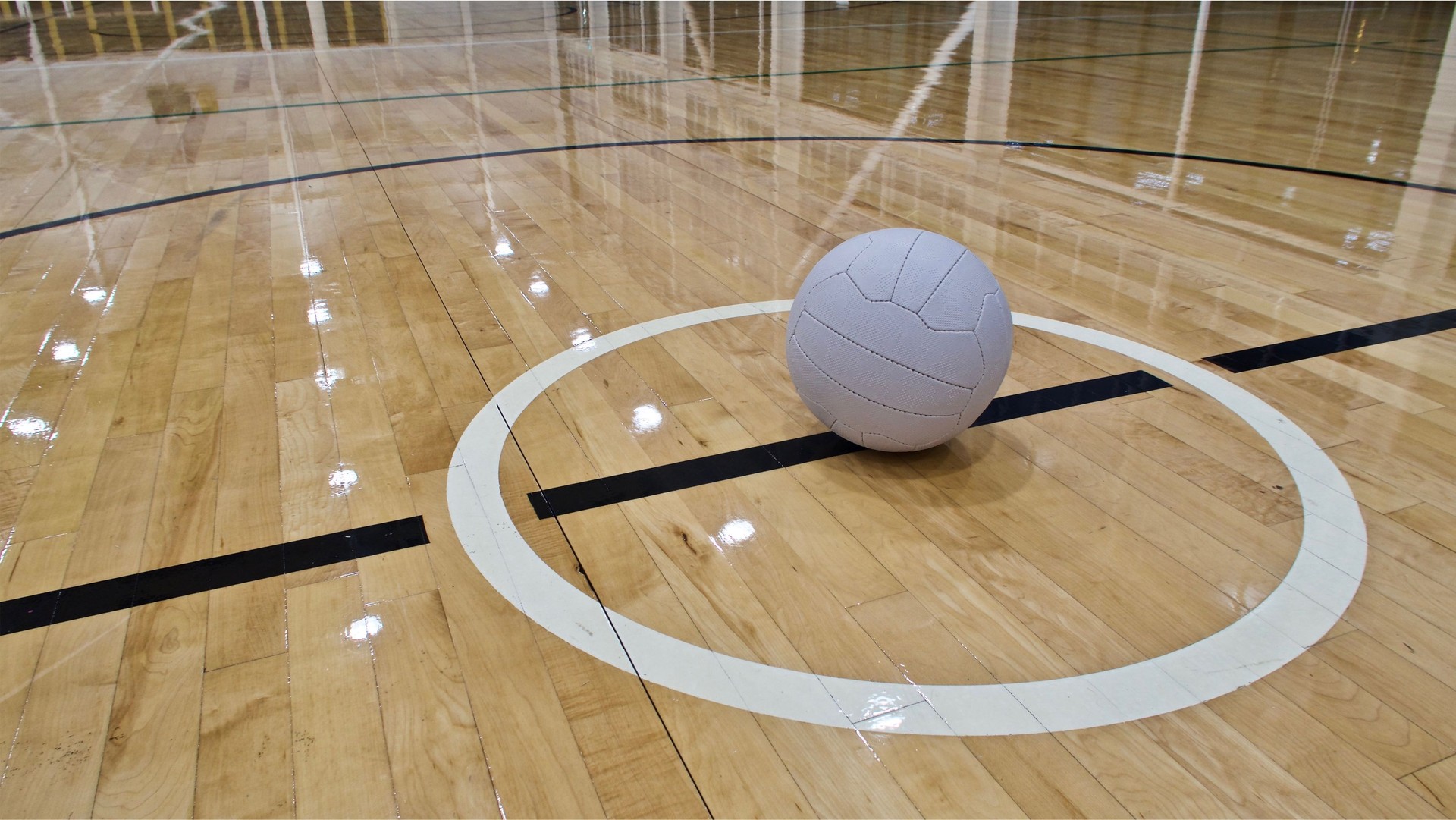 A Netball Ball placed in the centre circle of an indoor Netball court